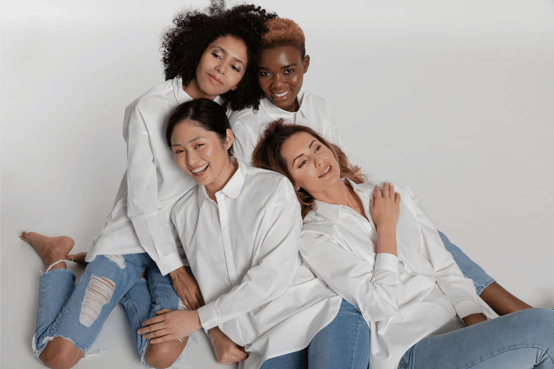 Four models of different ethnic backgrouds smiling while wearing white cotton shirt from Gracelandic