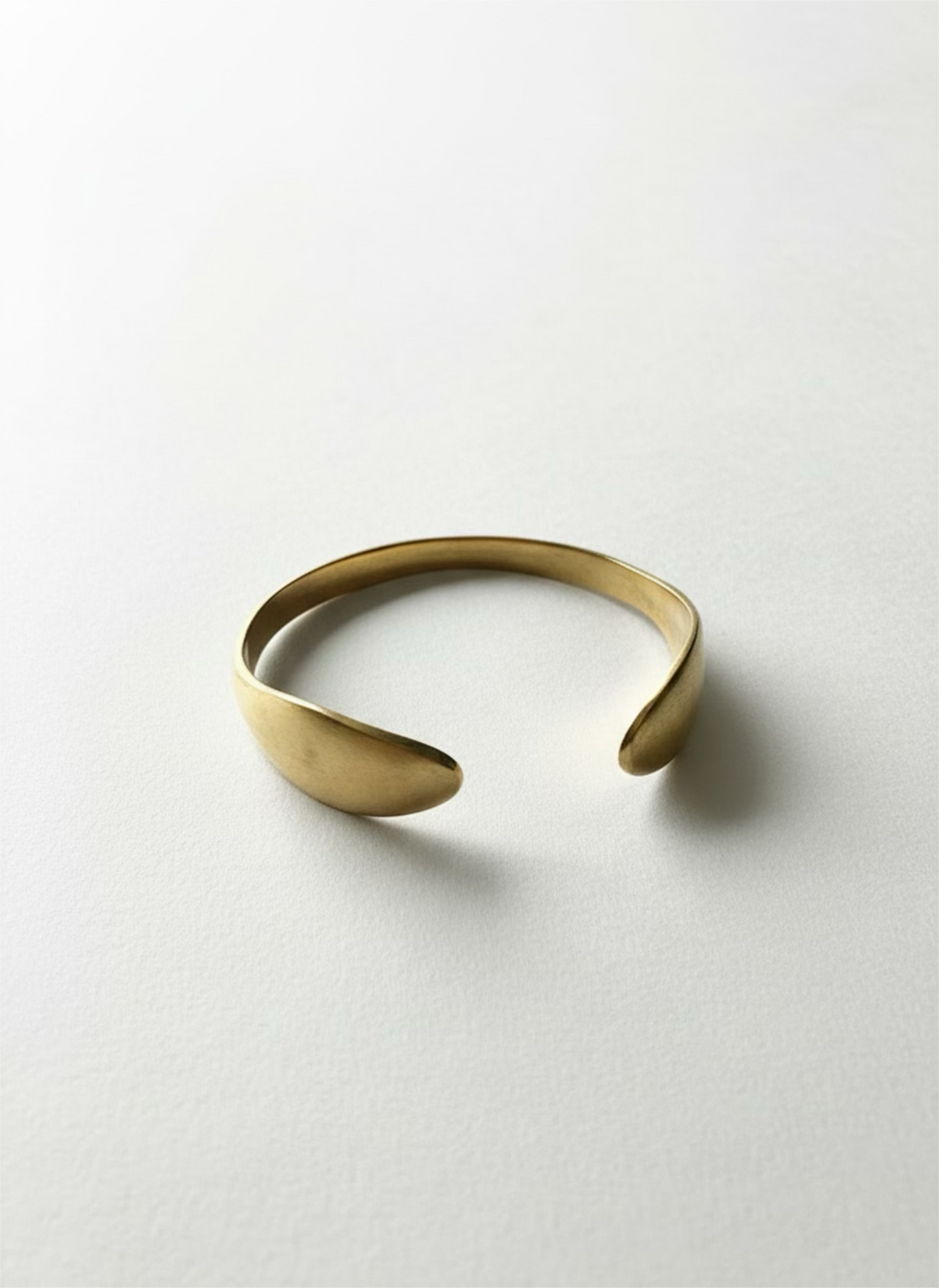 Open cuff crafted from yellow brass with a geometric design, featuring a wide band and adjustable fit.