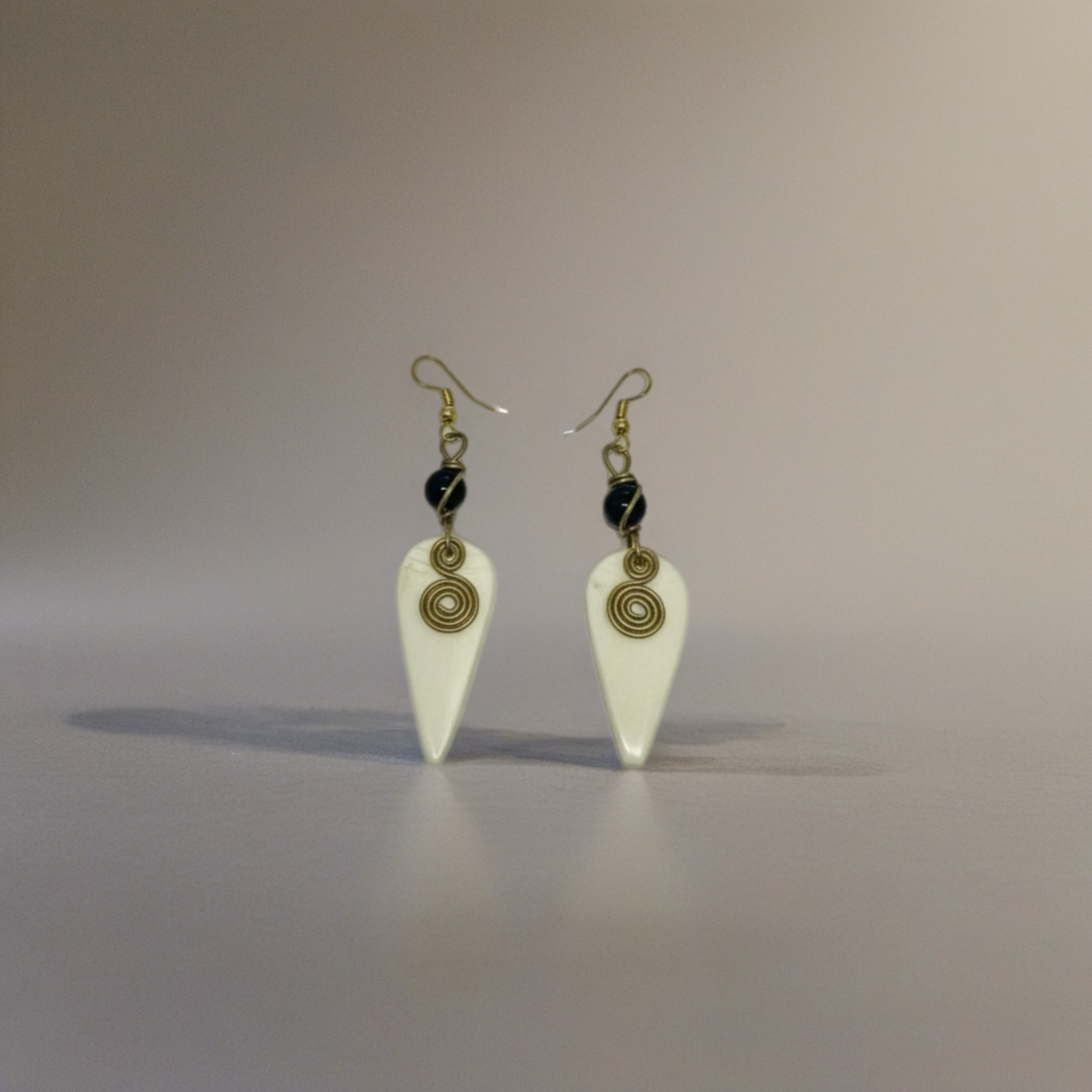 Drop earrings featuring a geometric charm in warm yellow brass with wire-wrapped detailing and a hook closure.