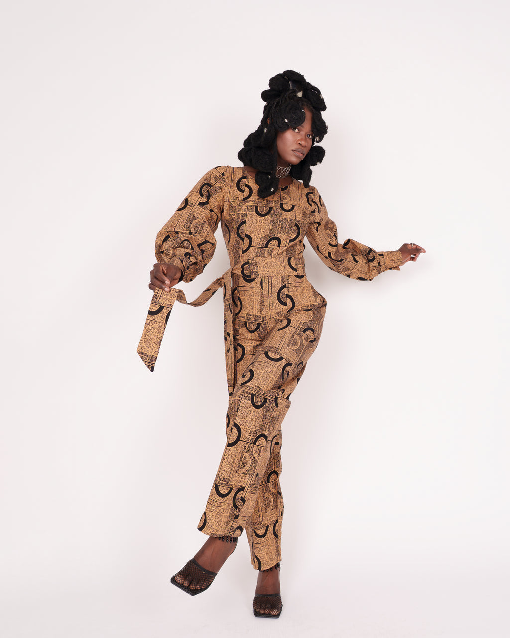 Jumpsuit featuring long balloon sleeves, a fitted waist with a detachable belt, and straight ankle-length pants adorned with an abstract pattern.