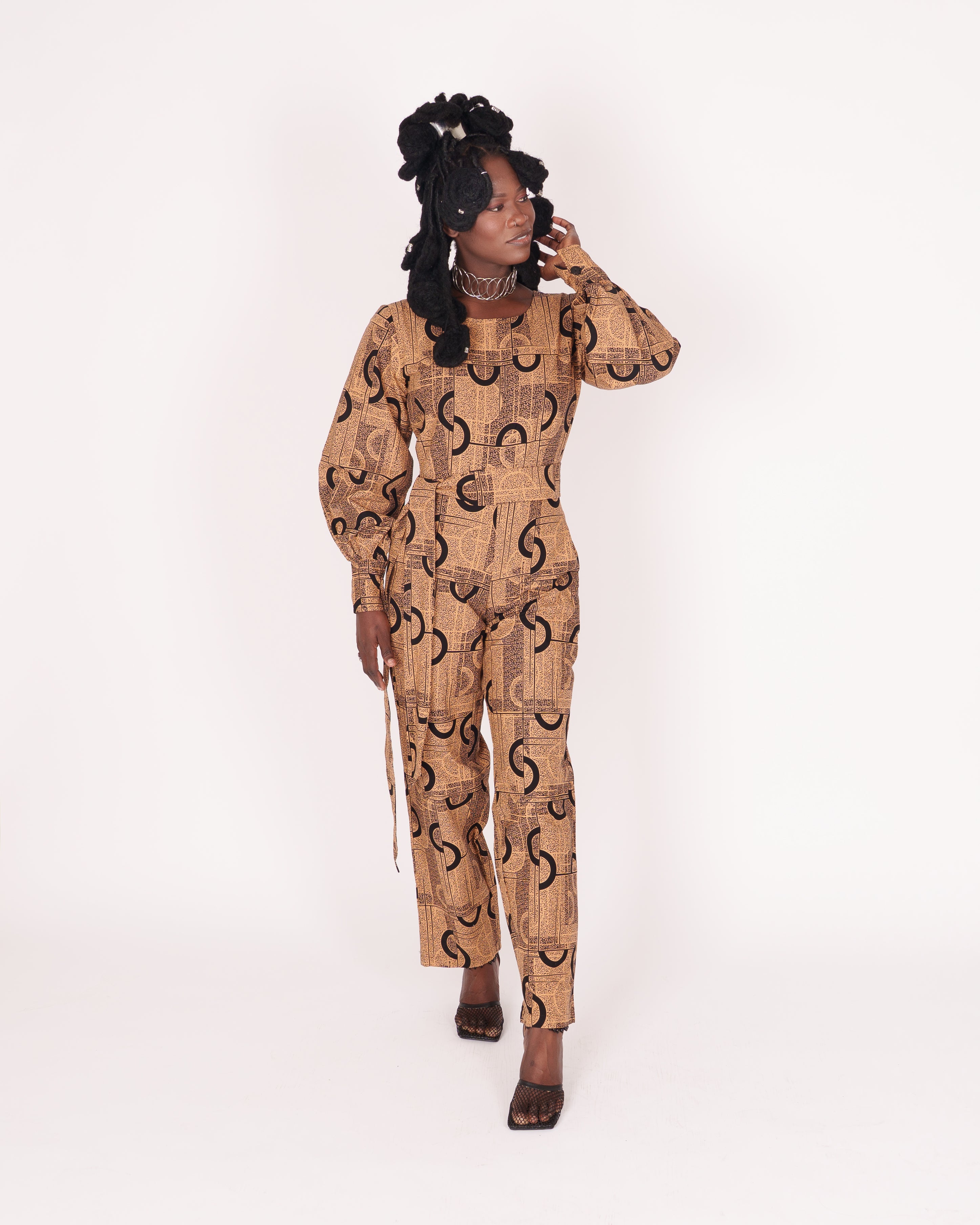 Jumpsuit featuring long balloon sleeves, a fitted waist with a detachable belt, and straight ankle-length pants adorned with an abstract pattern.